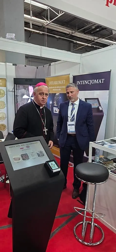 Gespräch an einem Messestand vor einem Spendenautomaten mit Kartenleser.